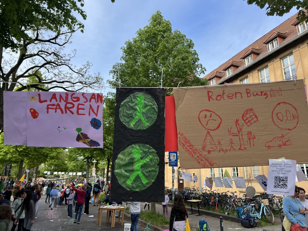 Für die Schulstraßenaktion hängen vor der Schule von den Kindern gemalte Plakate quer über der Rothenburg-Straße.