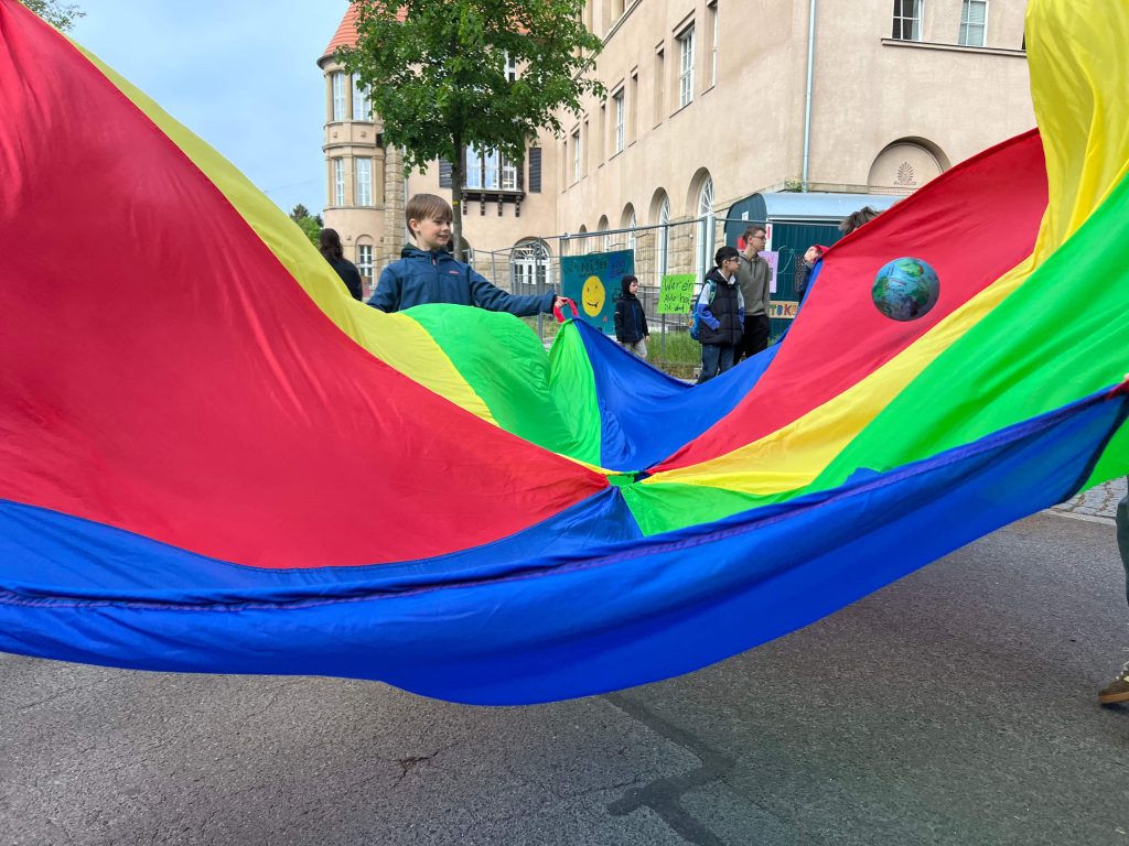 Während der Schulstraßenaktion spielen Kinder mit dem Schwungtuch auf der Straße vor der Rothenburg-Grundschule.