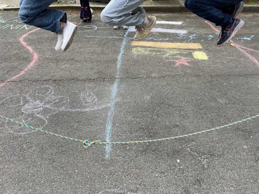 Während der Schulstraßenaktion springen Kinder Springseil.