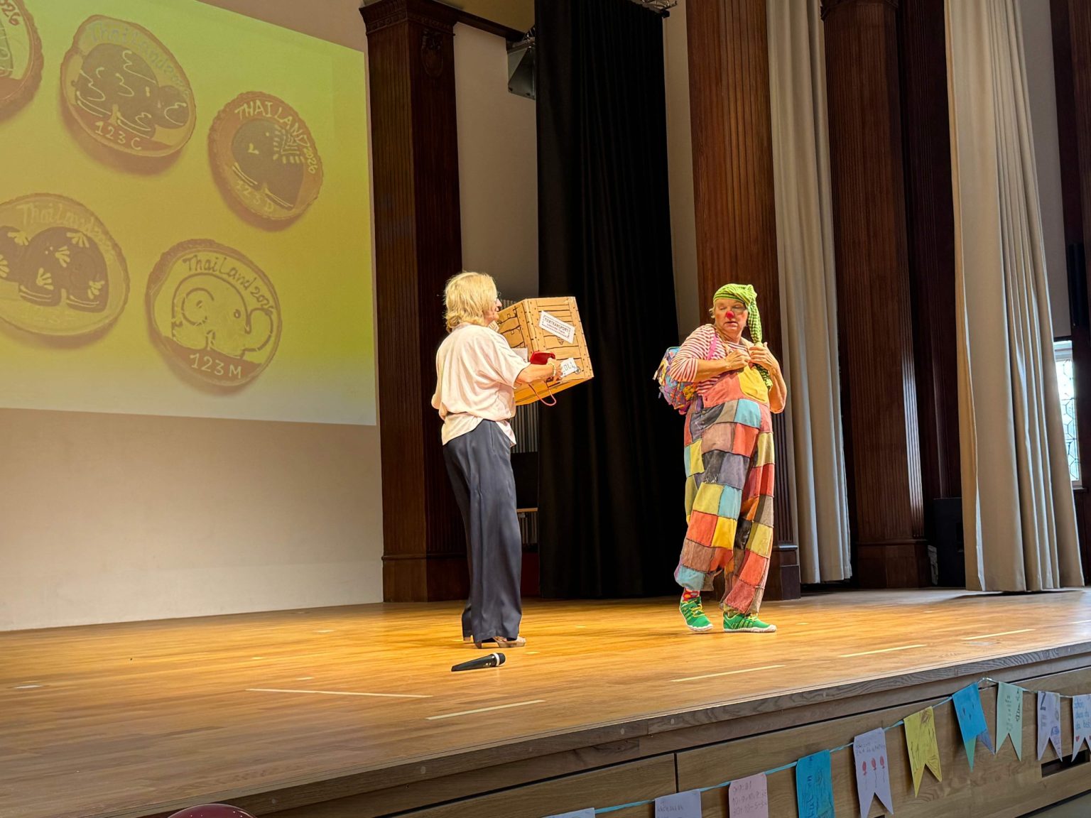 Die Schullleitung und Clown Schnuppe begrüßen die Erstklässler:innen und ihre Eltern in der Aula.